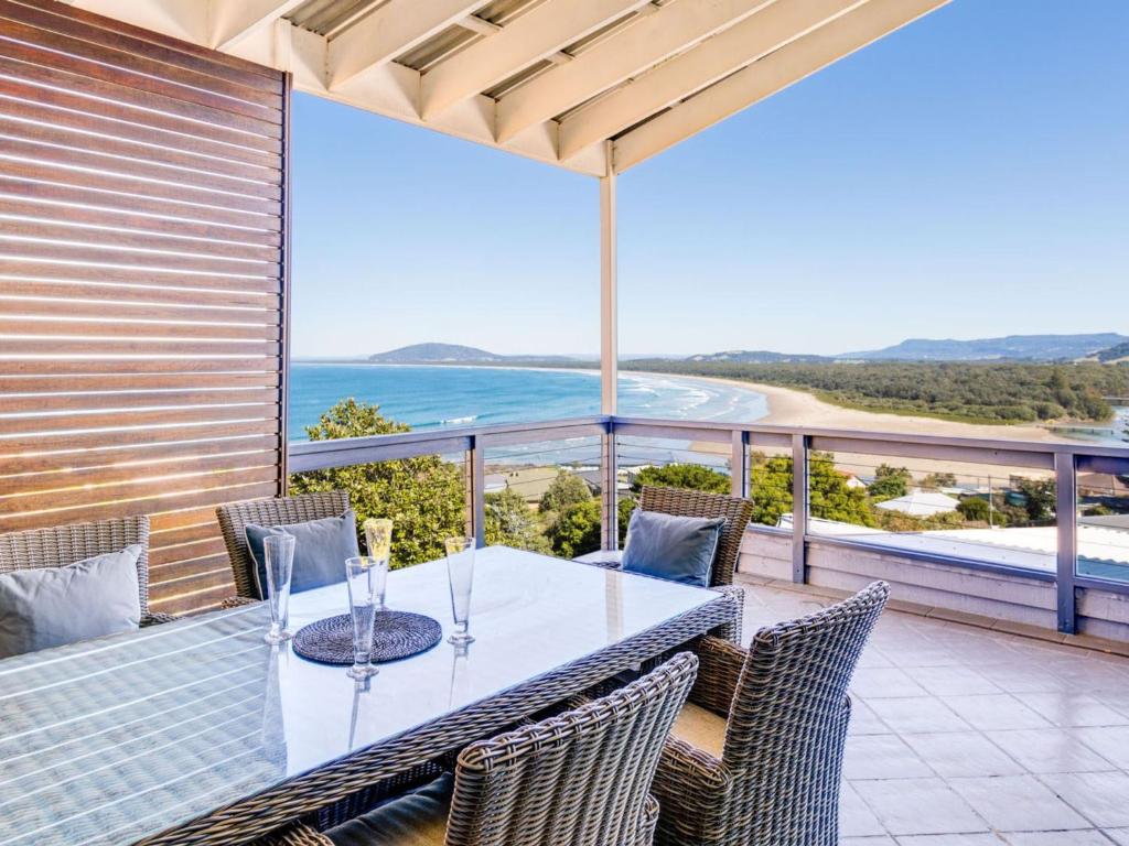 een tafel en stoelen op een balkon met uitzicht op de oceaan bij The Lookout at Gerroa in Gerroa