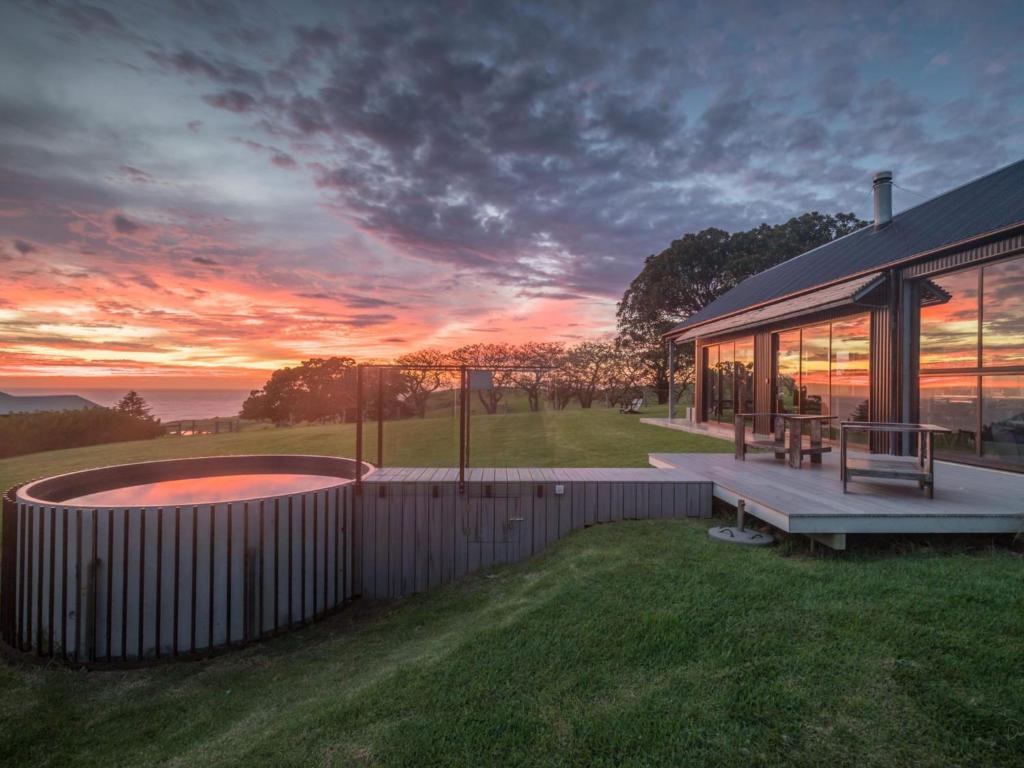 a house with a bench and a hot tub in the grass at The Shed Gerroa in Gerroa