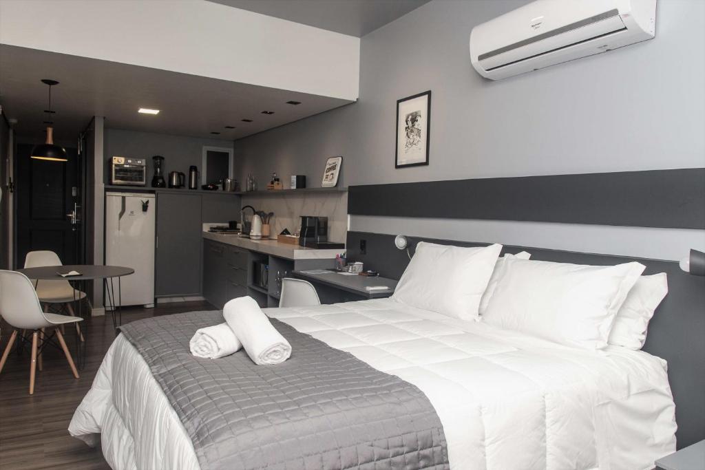 una camera con un grande letto bianco e una cucina di Studio 107/Floripa - Estilo no coração da cidade a Florianópolis