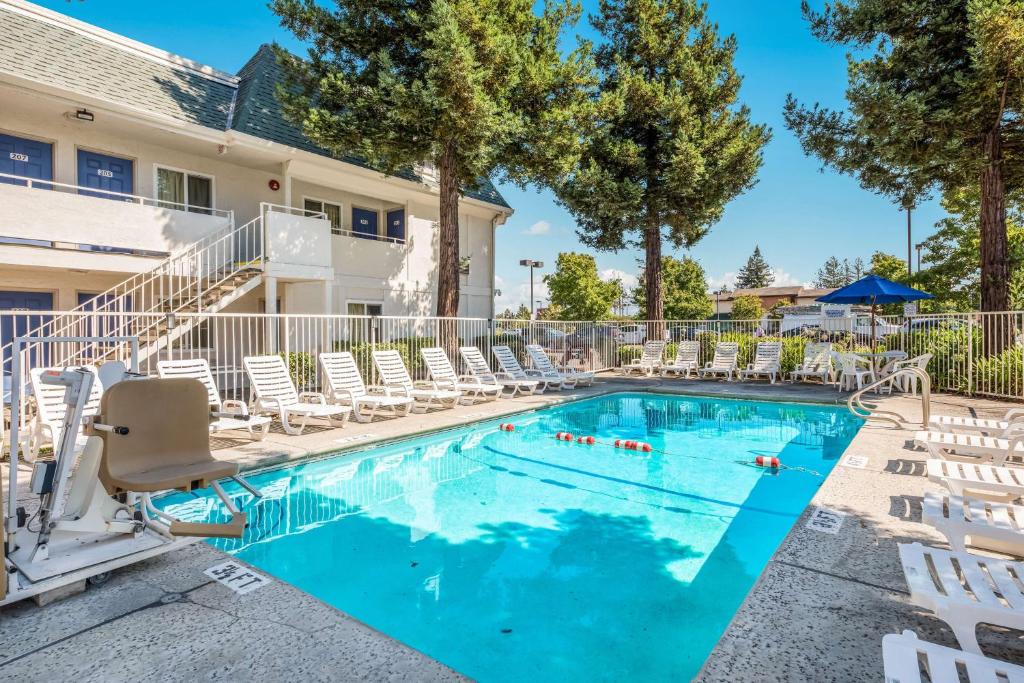 a swimming pool with chaise lounge chairs and a resort at Motel 6-Rohnert Park, CA in Rohnert Park