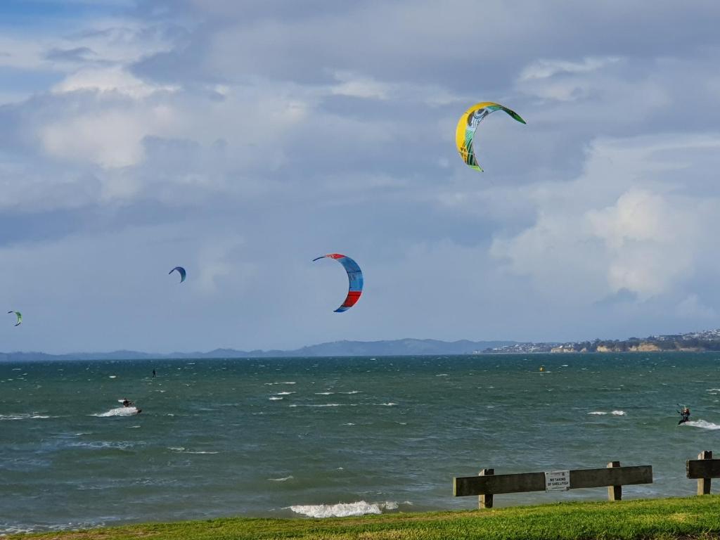 two kites flying over a body of water at Aqua On The Beach in Auckland