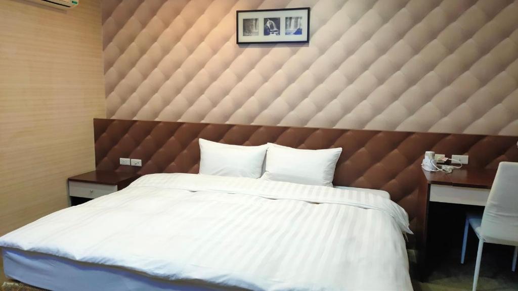 a bedroom with a large bed with a large padded wall at Shun-yi Business Hotel in Chiayi City