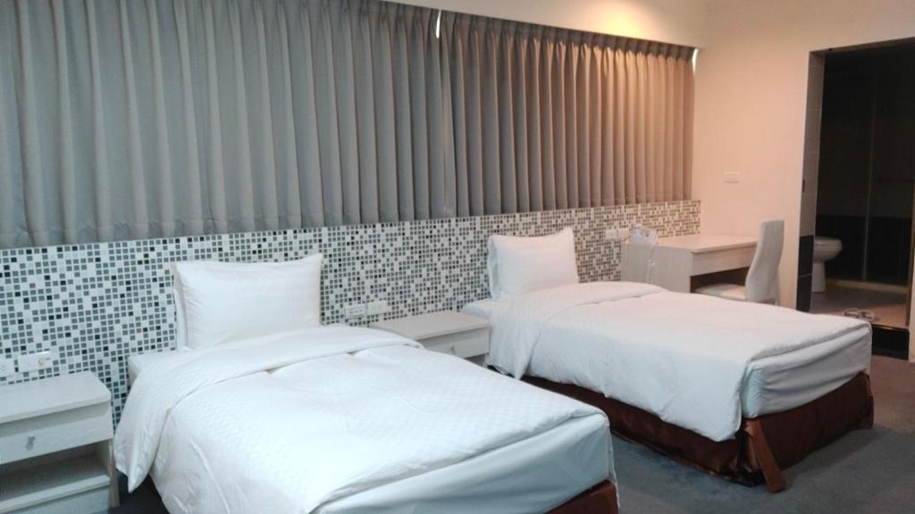 a hotel room with two beds and a desk at Shun-yi Business Hotel in Chiayi City
