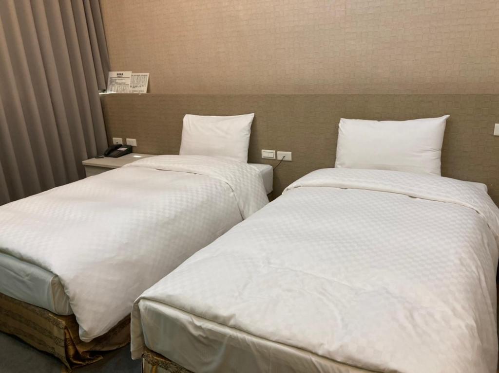 two beds sitting next to each other in a hotel room at Shun-yi Business Hotel in Chiayi City