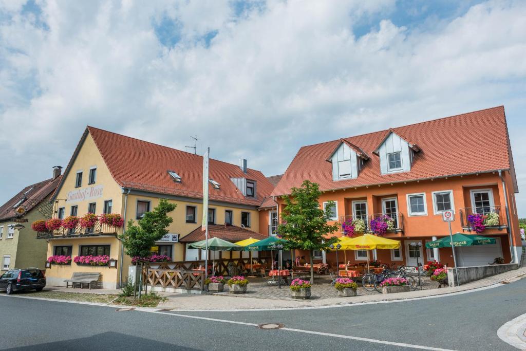 un edificio con mesas y sombrillas en una calle en Gasthof Rose, en Flachslanden