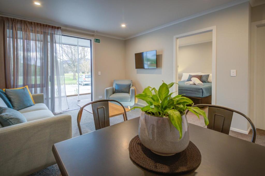 un salon avec un canapé et une table avec une plante dans l'établissement Dusky Motels, à Te Anau