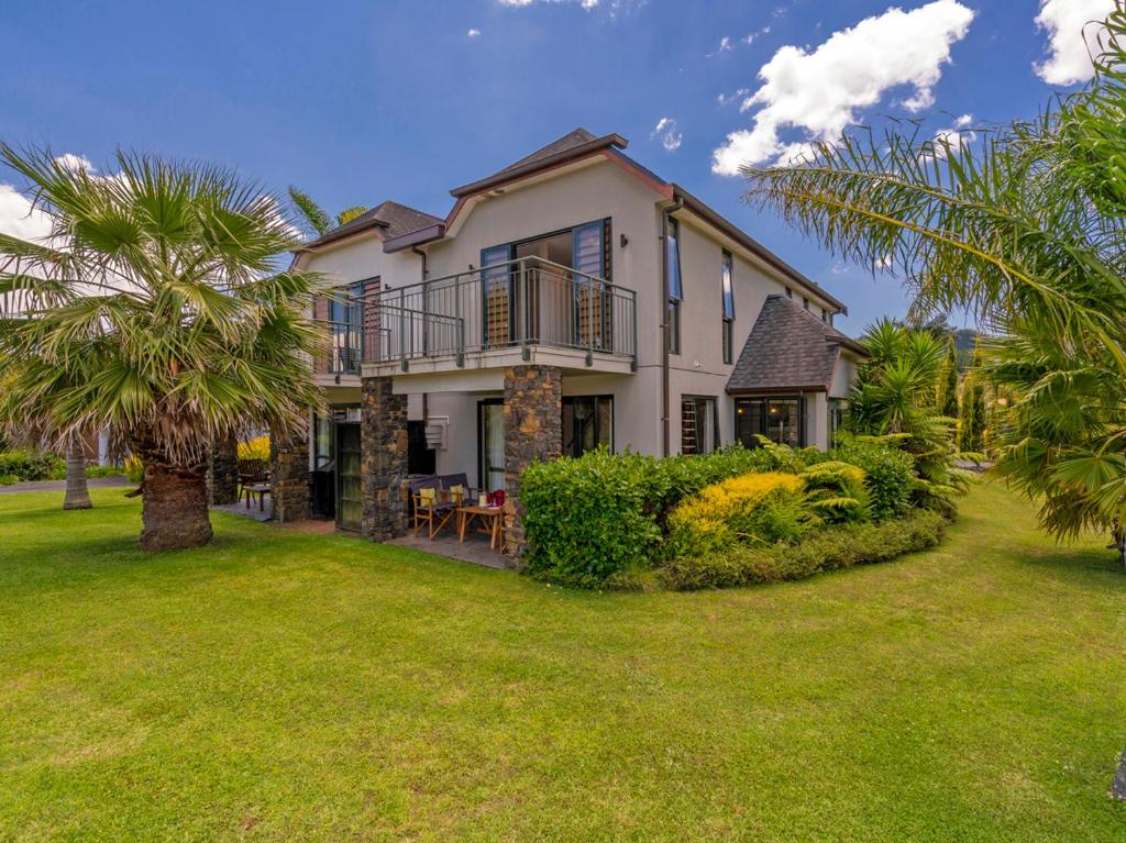a large house with a yard with palm trees at Villa 51 - Pauanui Holiday Home in Pauanui