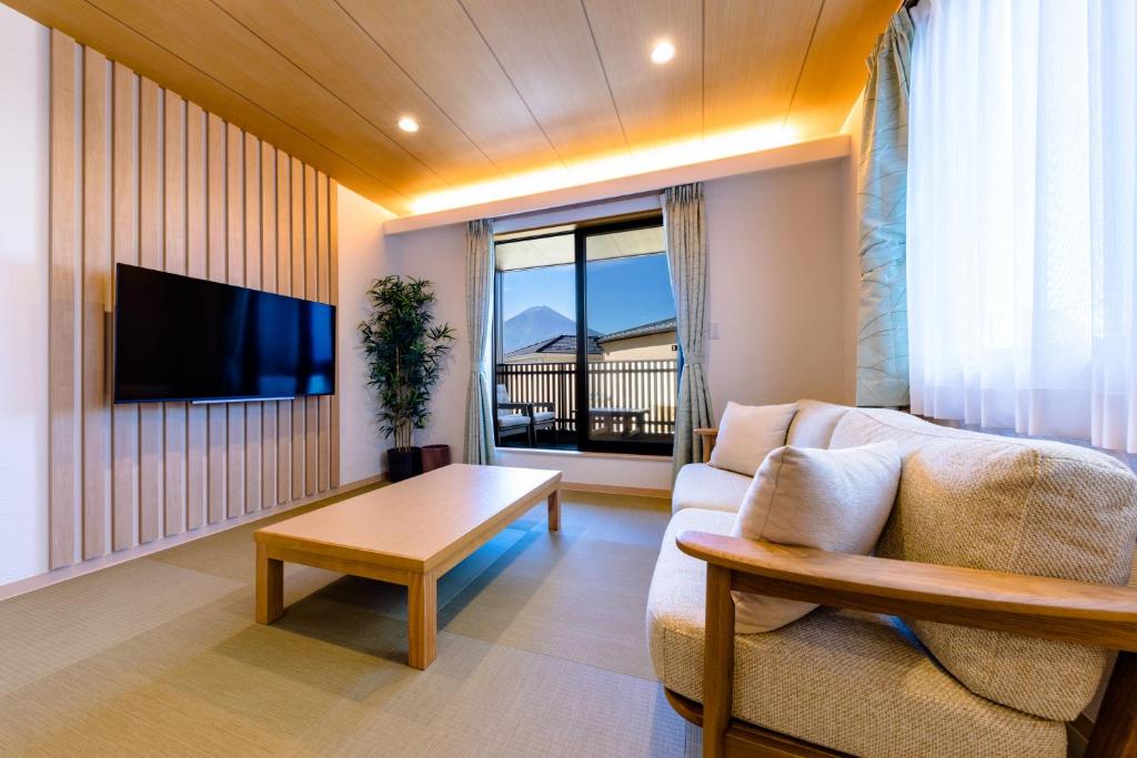 ein Wohnzimmer mit einem Sofa, einem TV und einem Tisch in der Unterkunft 03 Resort Club -雅MIYABI- in Fujikawaguchiko