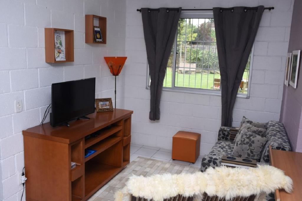 sala de estar con TV y sofá en Apartamento Canela Bela, en Canela