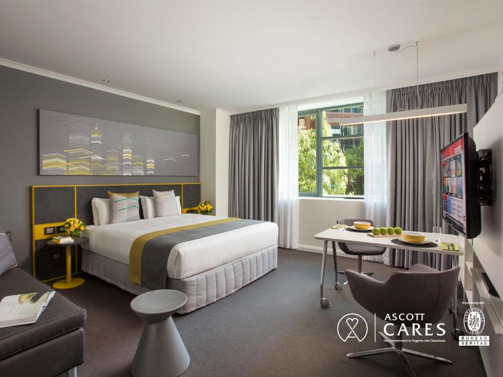 a hotel room with a large bed and a desk at Citadines St Georges Terrace in Perth