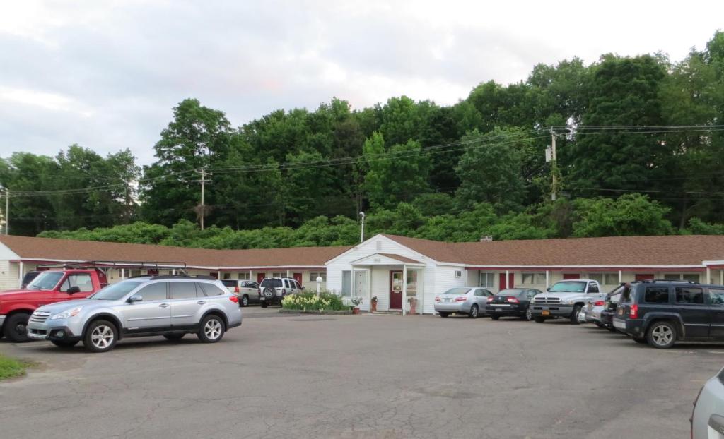 a building with cars parked in a parking lot at Cortland Motel in Cortland