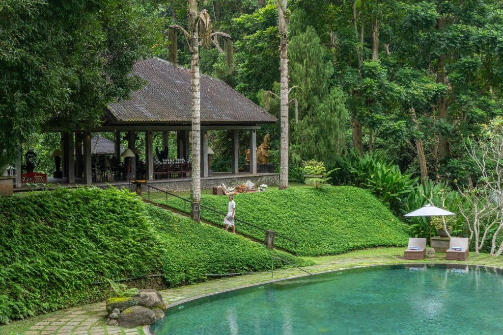 a person standing near a swimming pool in a garden at Dua Dari, a Residence by Hadiprana in Ubud