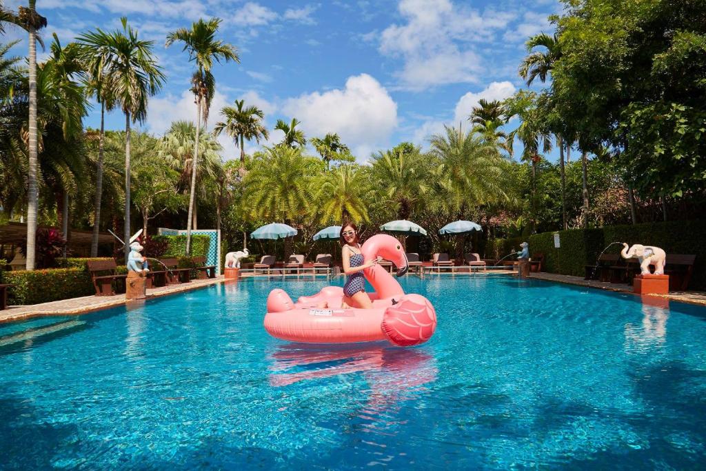 a woman riding on a pink raft in a swimming pool at Villa Wanida Garden Resort in Pattaya North
