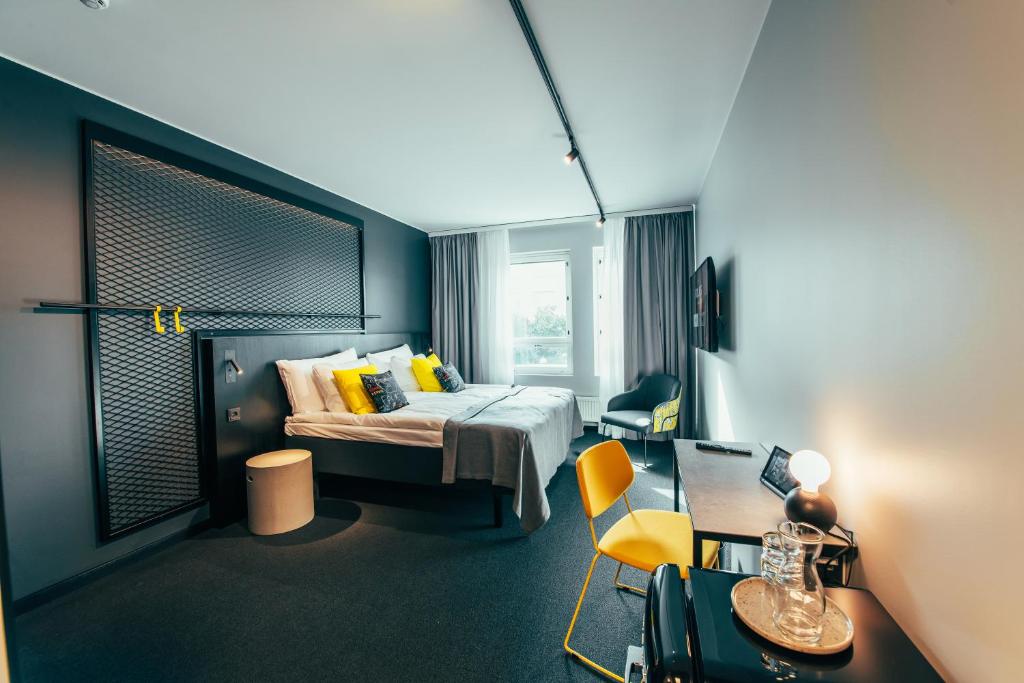 a hotel room with a bed and a desk and a chair at The Folks Hotel Konepaja in Helsinki