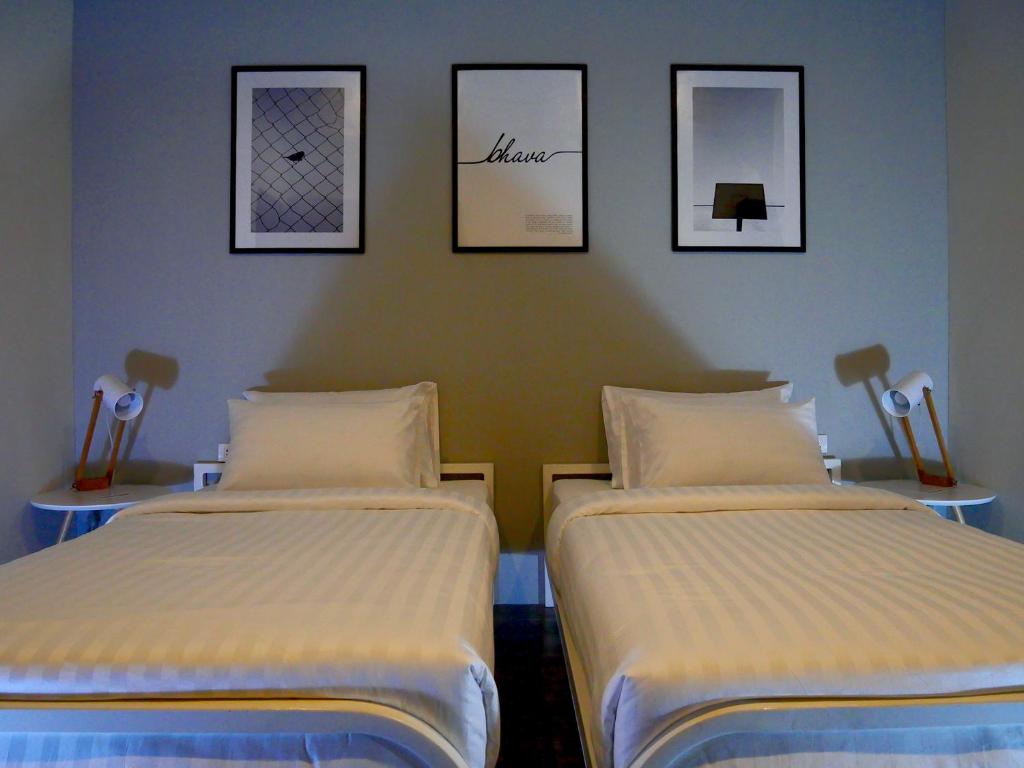 two beds in a room with pictures on the wall at Bhava Residence in Hat Yai