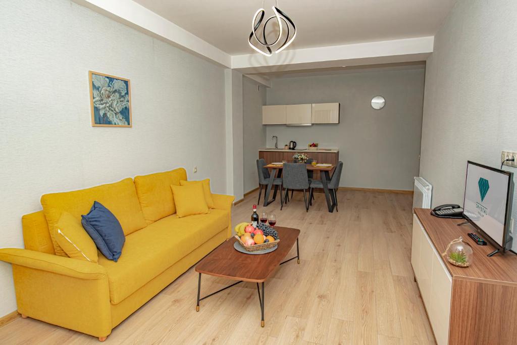 a living room with a yellow couch and a table at Crystal Residence in Bakuriani