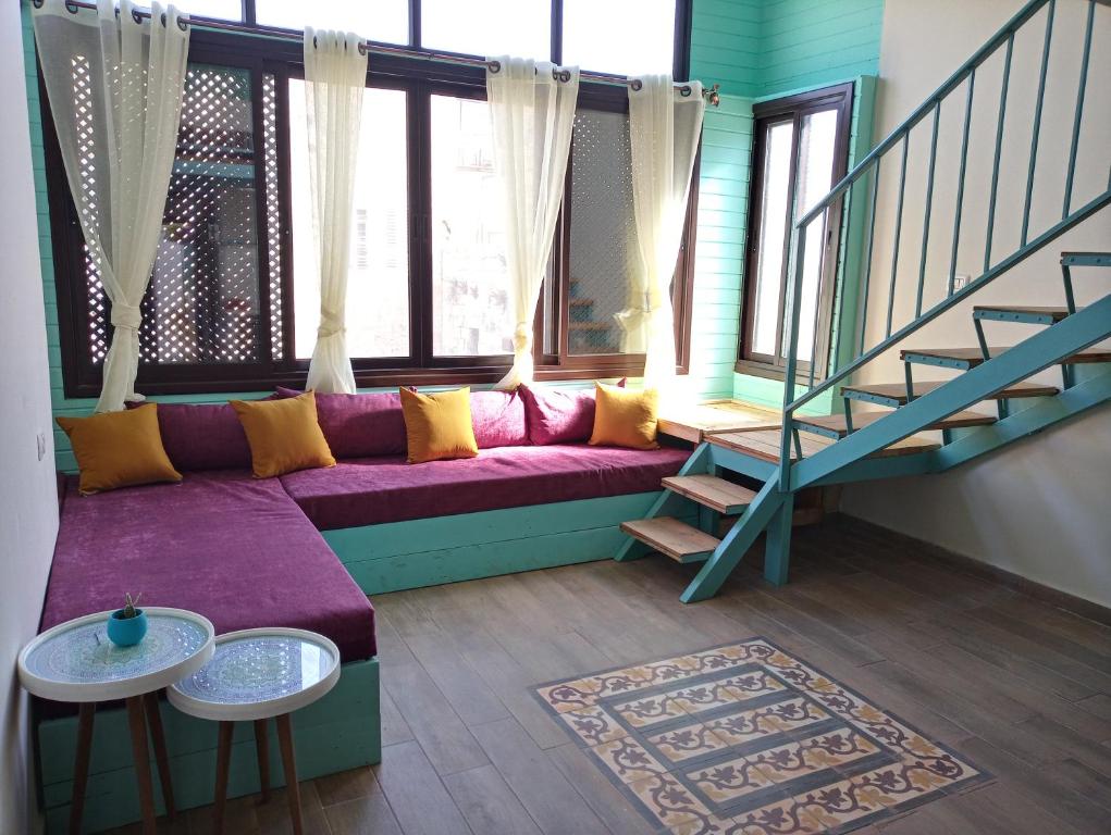 a living room with a purple couch and a staircase at Turquoise in Nablus