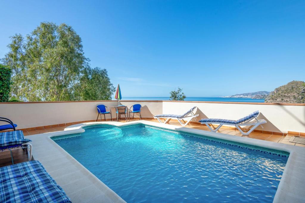 una piscina con sillas y vistas al océano en 2 bedrooms house at Nerja 300 m away from the beach with sea view private pool and furnished terrace, en Nerja