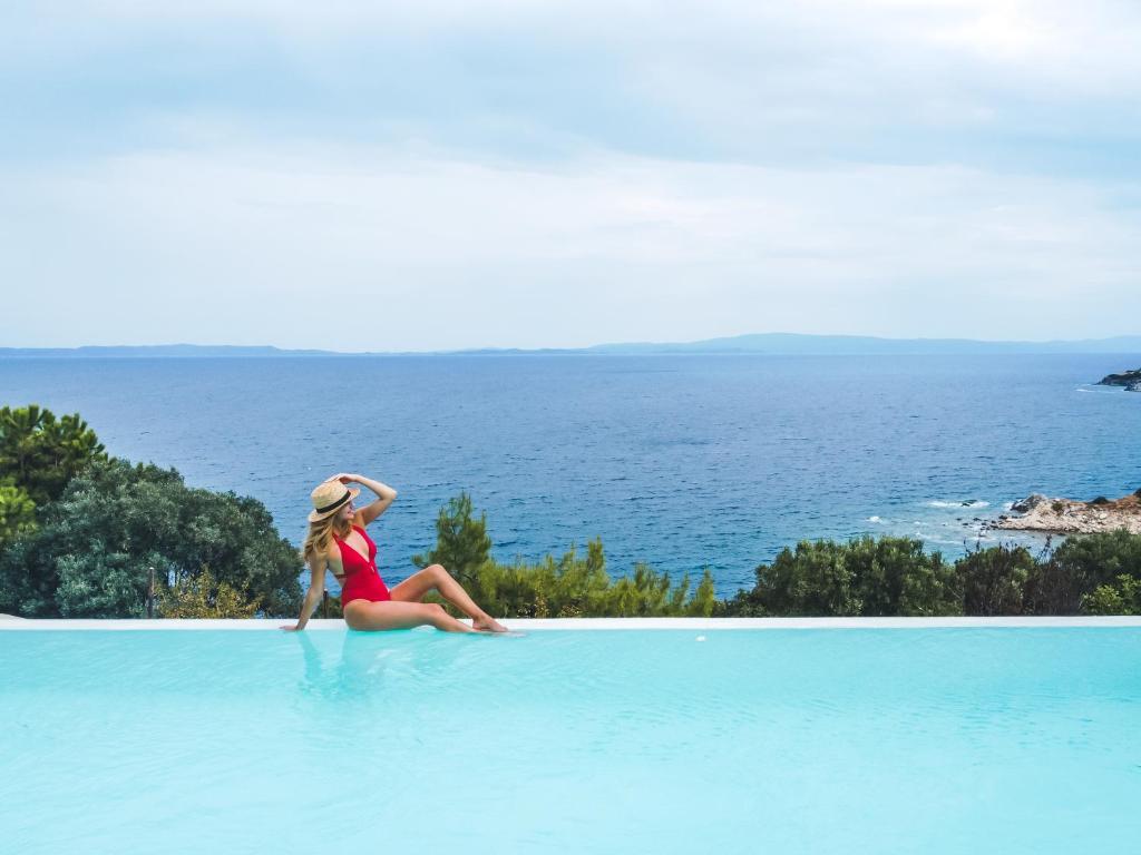 a little girl sitting on the edge of a swimming pool at Nissi View Villa in Vourvourou