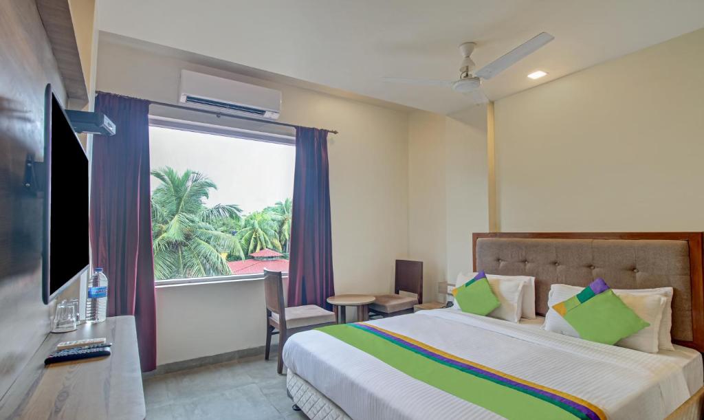 sypialnia z łóżkiem i dużym oknem w obiekcie Itsy By Treebo - Tao Residency 2 Minutes Walk From Baga Beach w mieście Stare Goa