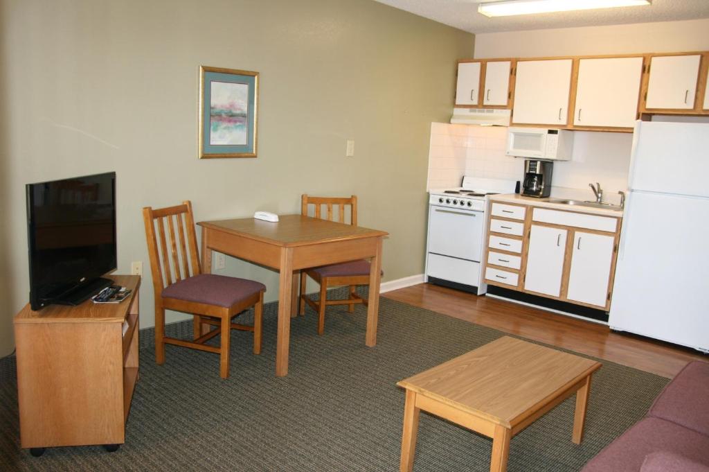 a living room with a kitchen and a table with chairs and a refrigerator at Affordable Suites Salisbury in Salisbury