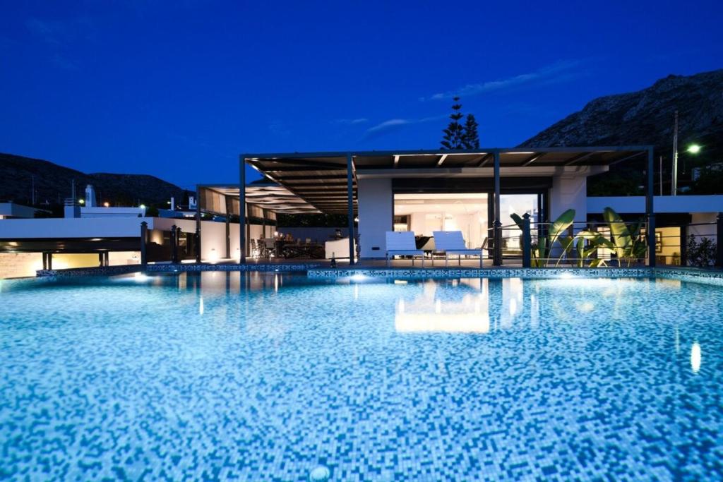 una grande piscina di fronte a una casa di notte di Luxury Beachfront Villa Selenia Platinum in Sounio a Sounio