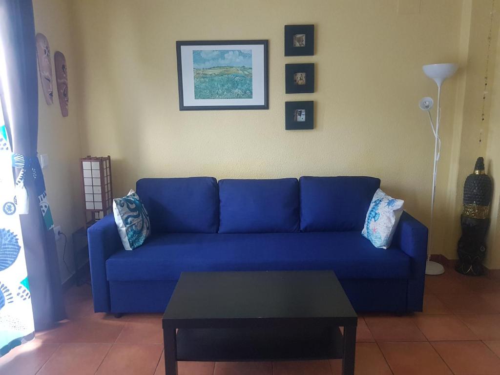 un divano blu in soggiorno con tavolo di Casa Beatriz a Cala San Vicente