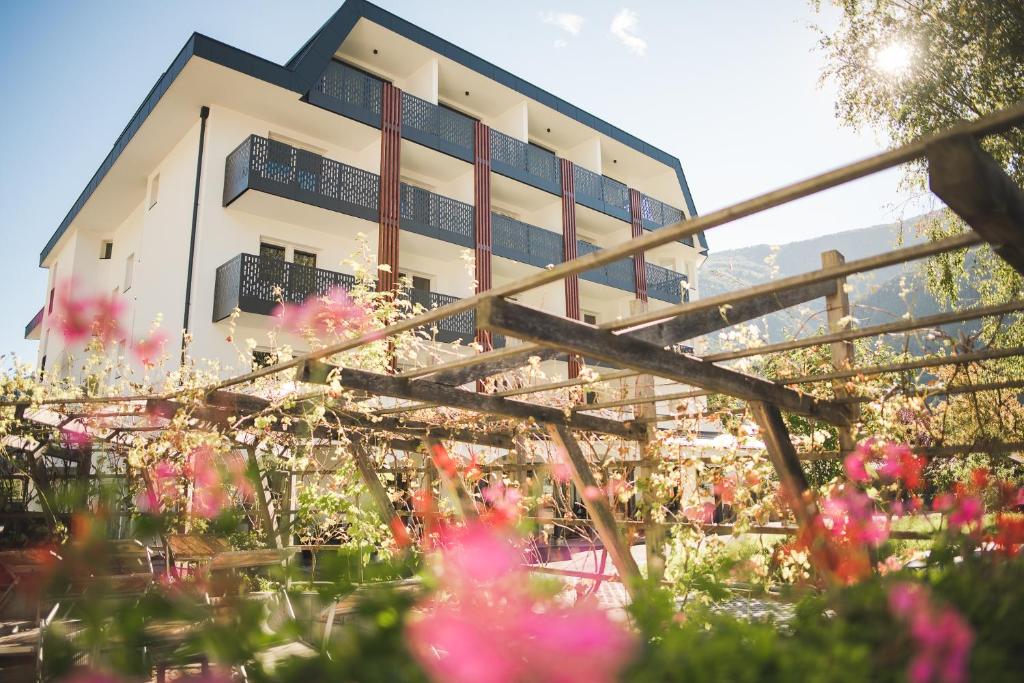 un edificio con flores rosas delante de él en Park Hotel Villa Etschland, en Plaus