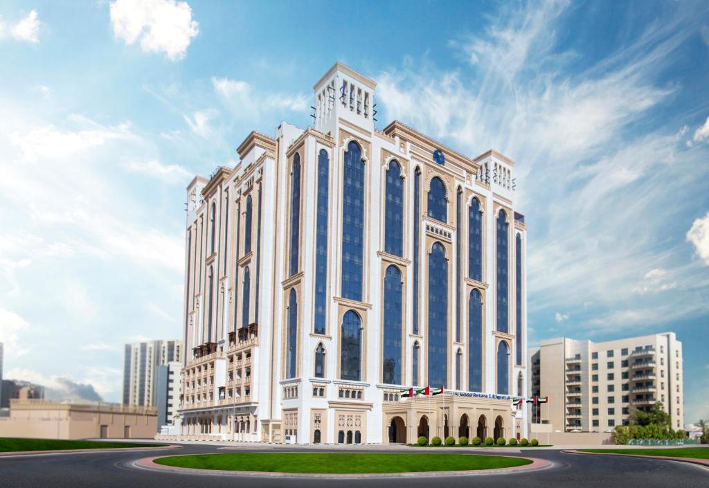 a large white building with blue windows at Al Jaddaf Rotana Suite Hotel in Dubai