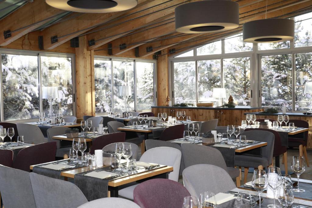 a dining room with tables and chairs and windows at Le Pic Blanc in L'Alpe-d'Huez