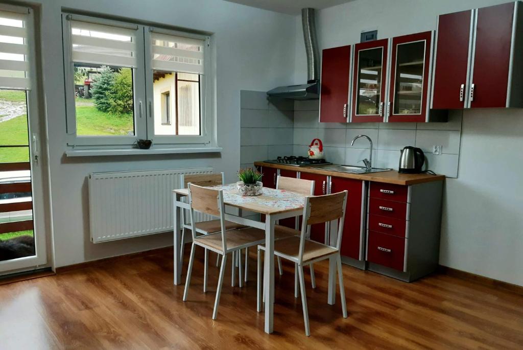 uma cozinha com armários vermelhos, uma mesa e cadeiras em U Górala Tadzia em Krynica-Zdrój