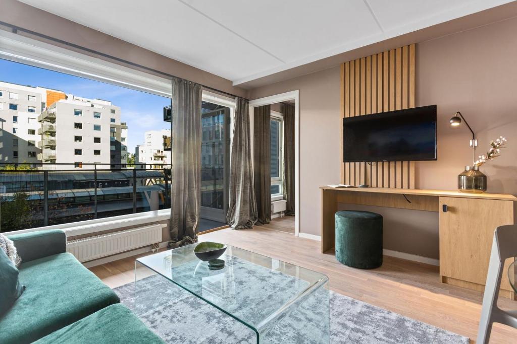 Una sala de estar con un sofá y una ventana grande. en BJØRVIKA APARTMENTS, Teaterplassen, Oslo city center, en Oslo