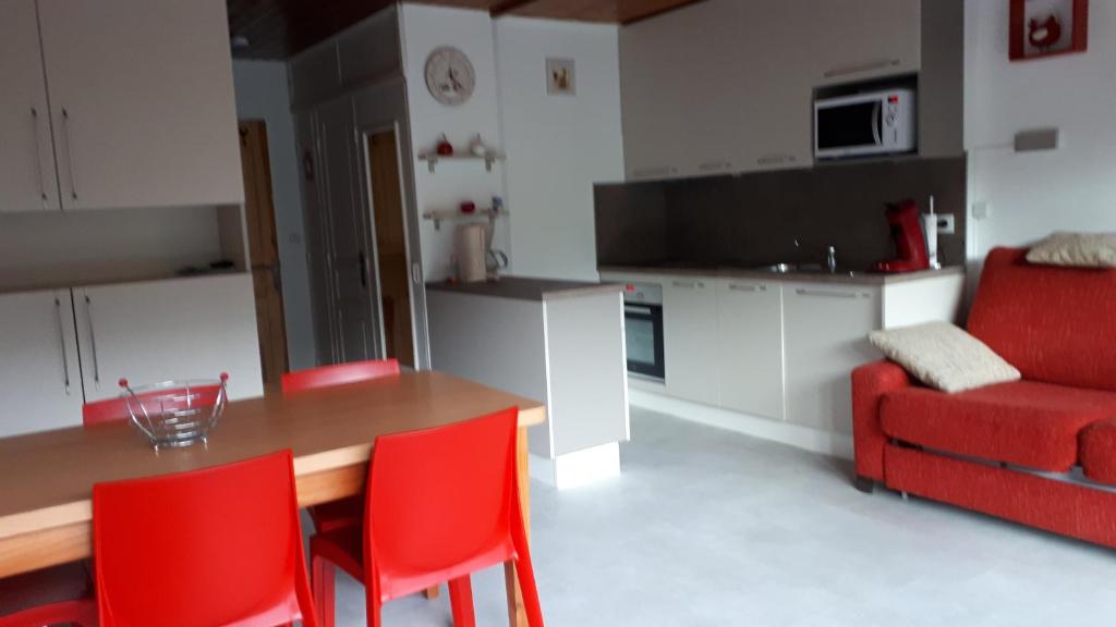une cuisine avec une table en bois et des chaises rouges dans l'établissement résidence Le Platé, aux Carroz d'Arâches