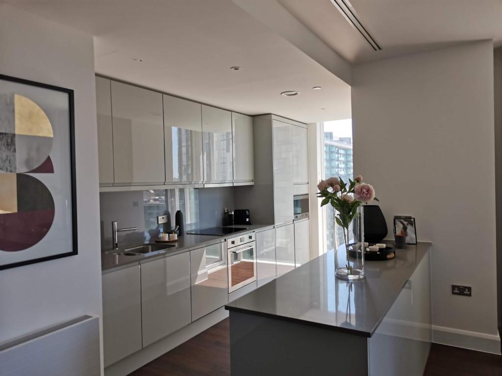 a kitchen with white cabinets and a vase of flowers on a counter at Canary Wharf by Charles Hope in London
