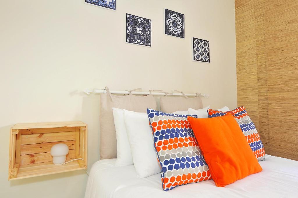 Una cama blanca con almohadas coloridas encima. en Cosy Bedrooms Guest House en Lisboa