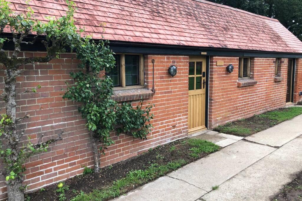 einem roten Backsteinhaus mit gelber Tür in der Unterkunft Luxury 2 Bed Cottage in the Orchard of a 17th Century Manor House in Colchester