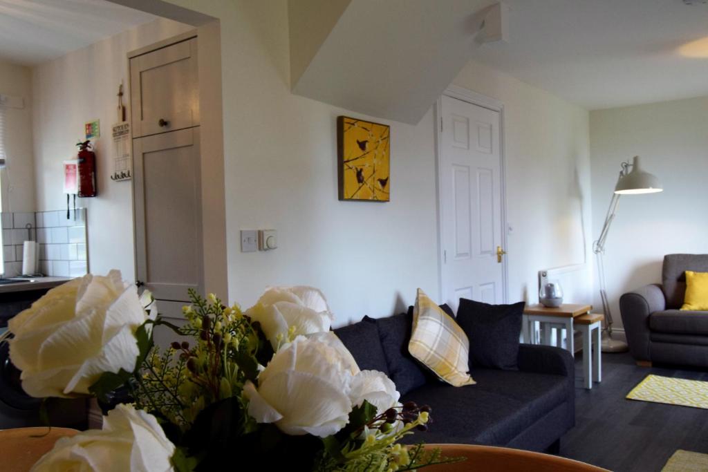 a living room with a couch and a clock on the wall at Woodlands View in Halesworth