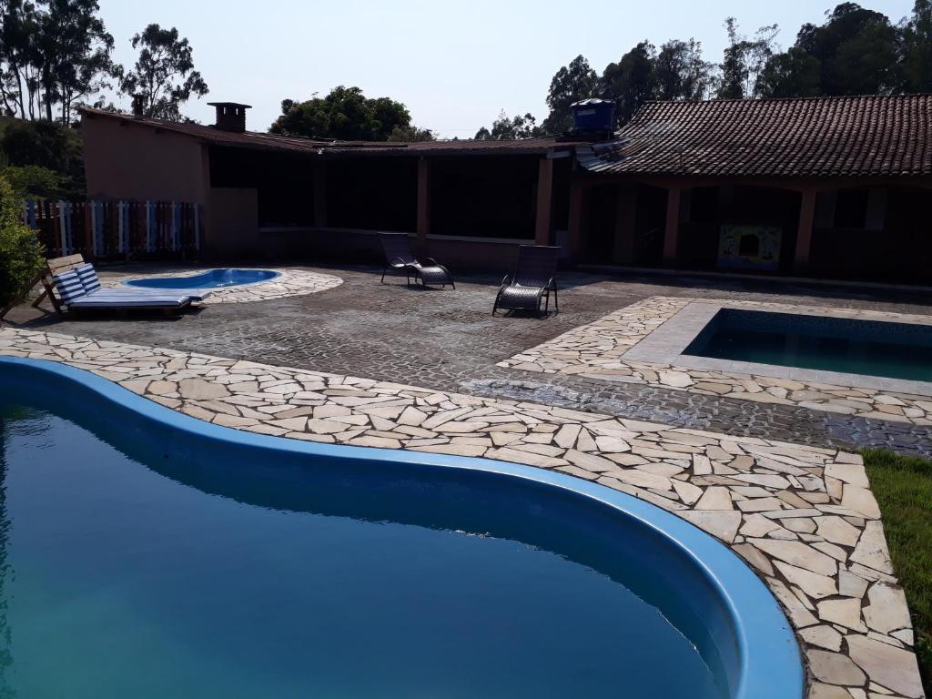 a swimming pool in a yard next to a house at Sítio Lírio do Vale- Munhoz, MG in Munhoz