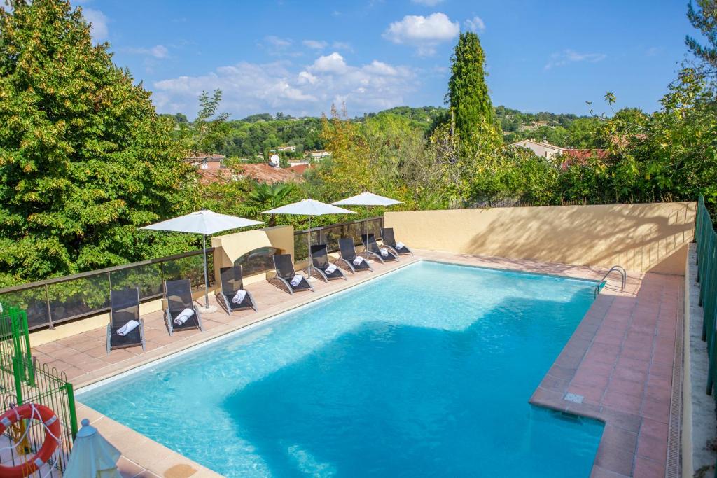 a swimming pool with chairs and umbrellas at Le Club Mougins in Mougins