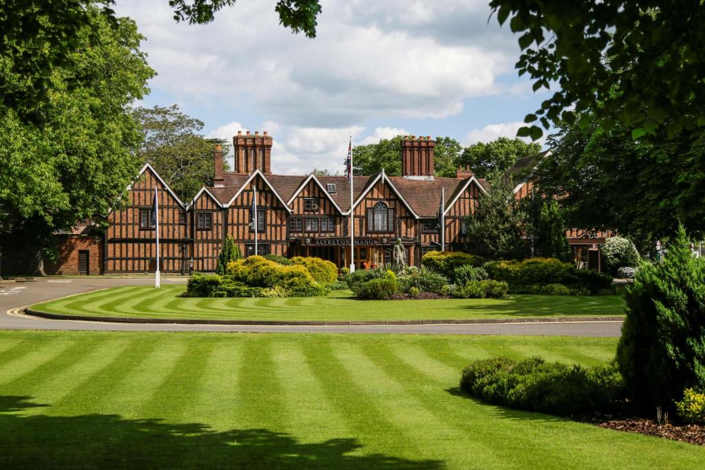 an old house with a lawn in front of it at Macdonald Alveston Manor Hotel & Spa in Stratford-upon-Avon
