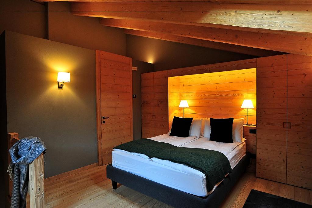 um quarto com uma cama grande e paredes de madeira em Alpi & Golf Hotel em Bormio