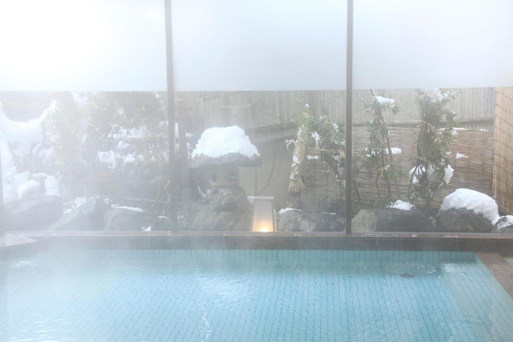 a swimming pool with snow on the windows of a building at Wafu-no-Yado MASUYA in Yamanouchi
