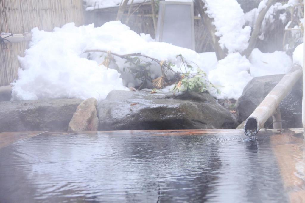 a pile of snow next to a body of water at Wafu-no-Yado MASUYA in Yamanouchi