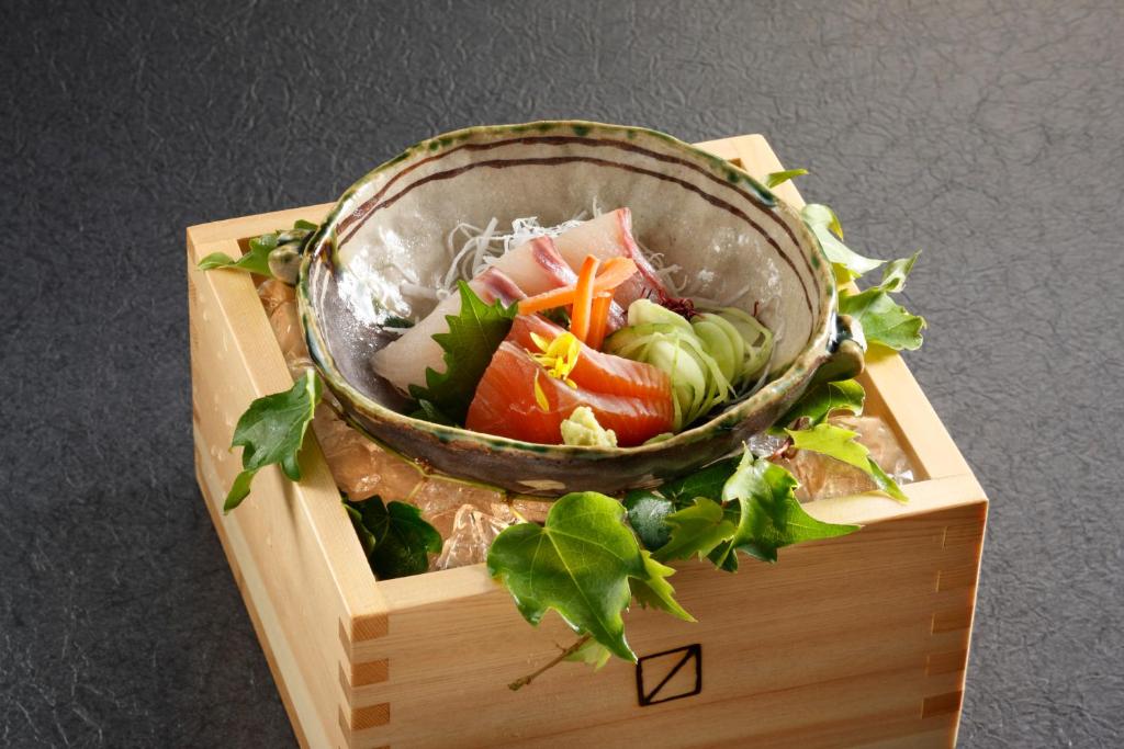 a bowl of vegetables on top of a wooden stand at Wafu-no-Yado MASUYA in Yamanouchi