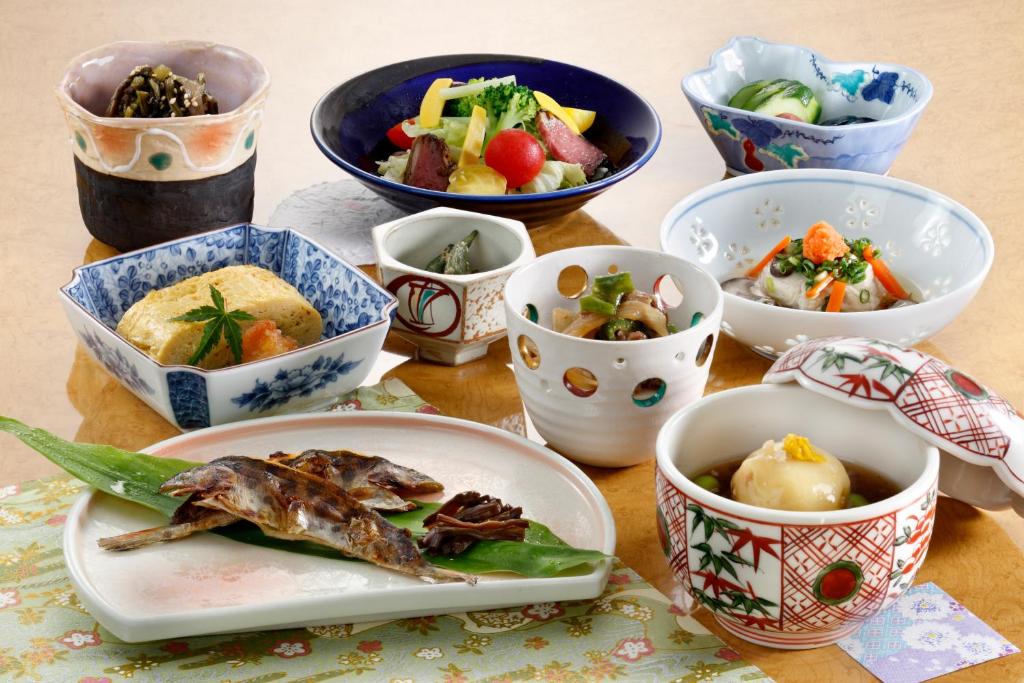 a table with bowls and plates of food on it at Wafu-no-Yado MASUYA in Yamanouchi