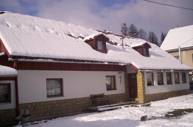 a house with snow on the roof of it at Chalupa u Drába in Oščadnica