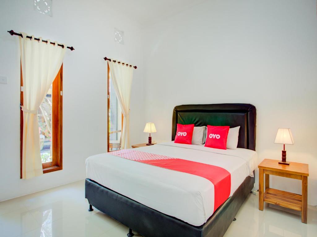 a bedroom with a bed with red pillows and a window at Vivaldi Jimbaran in Jimbaran