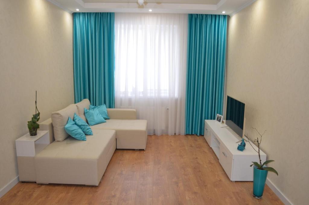 ein Wohnzimmer mit einem weißen Sofa und einem TV in der Unterkunft Apartment on Getmana Vigovskogo 49 in Riwne