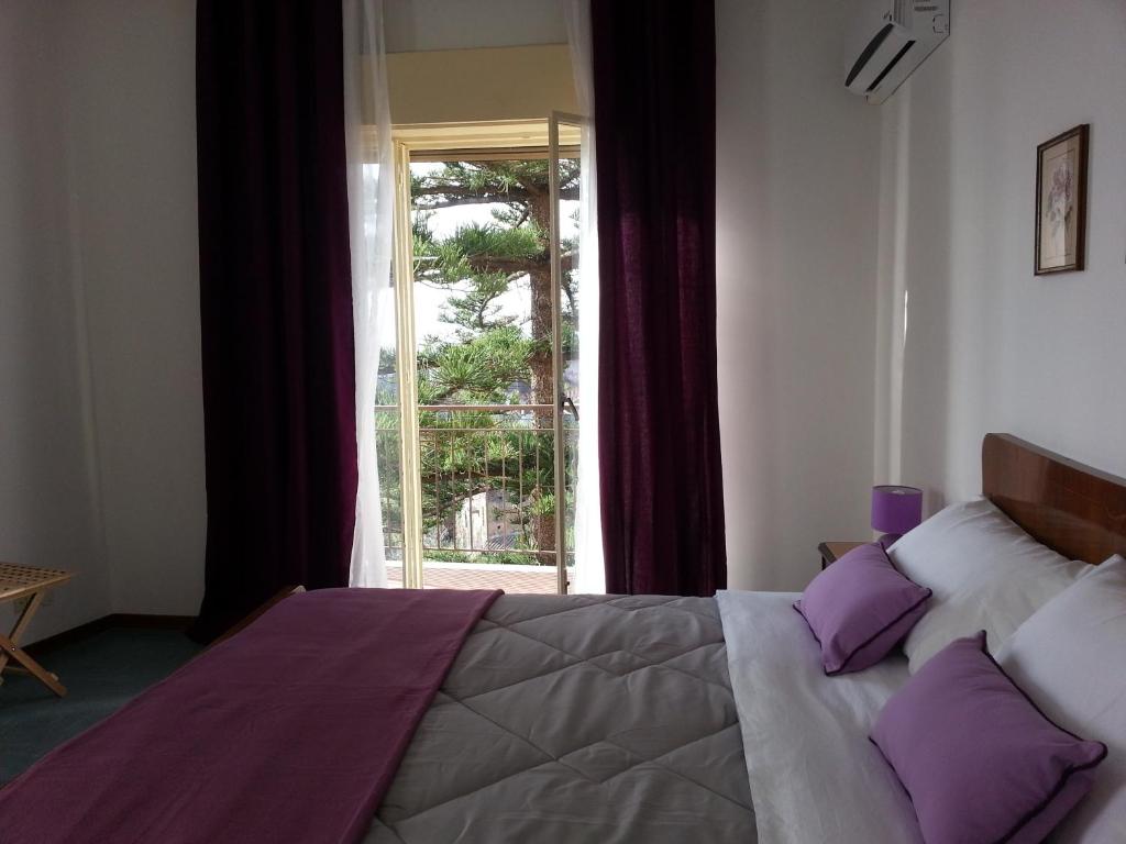 a bedroom with a bed with purple pillows and a window at Appartamento Raggio Di Sole in Acireale
