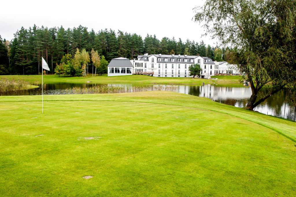 a golf course with a pond and a large building at Hotel Lipowy Most in Supraśl